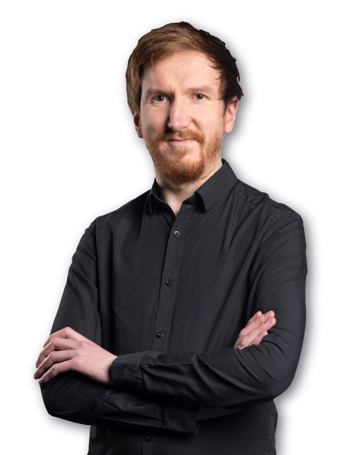 Peter smiling at the camera, wearing a black shirt with his arms folded.